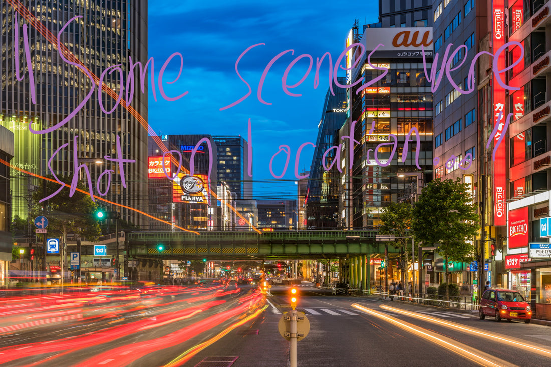 View of a Tokyo street, in low shutter speed to exaggerate the stream of car tail-lights heading into the distance. The photo looks toward the Ginza area of Tokyo. Graffiti overlay featuring a quote from the article: "Some scenes were shot on location…"