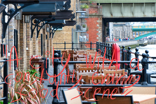 View of the an outdoors seating area at a London restaurant next to a canal, with two bridges going over the canal in shot. Graffiti overlay featuring a quote from the article: "A city with a constantly evolving food scene"