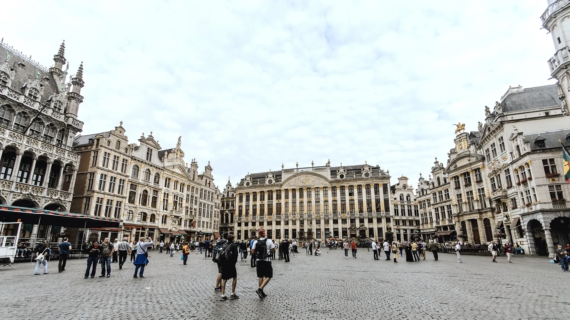 The Grand Place in the city of Brussels. It is a bright, but cloudy day and there is a handful of tourists milling about the area.