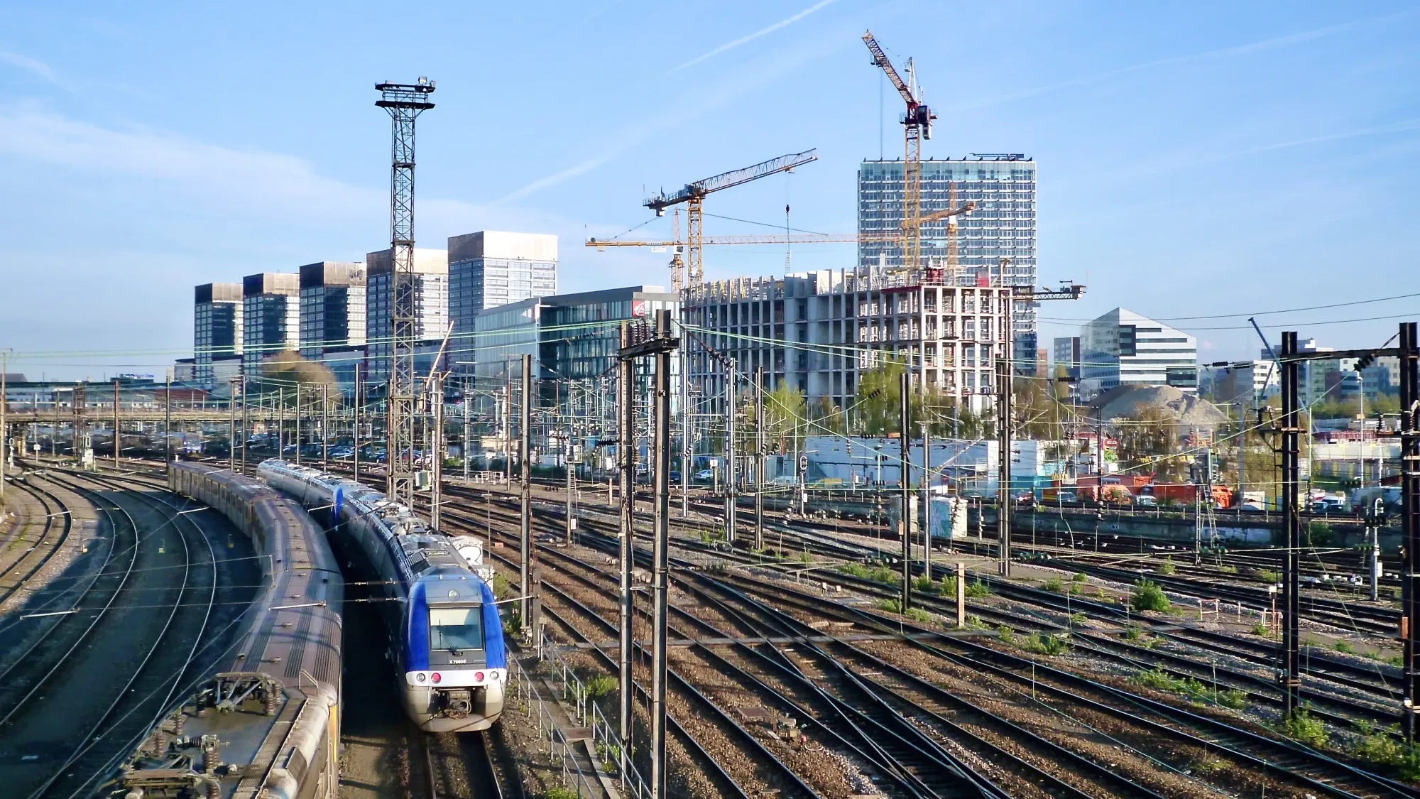 Lille train tracks, with a train coming towards the camera. In the background we can see the construction of the Euralille shopping centre.