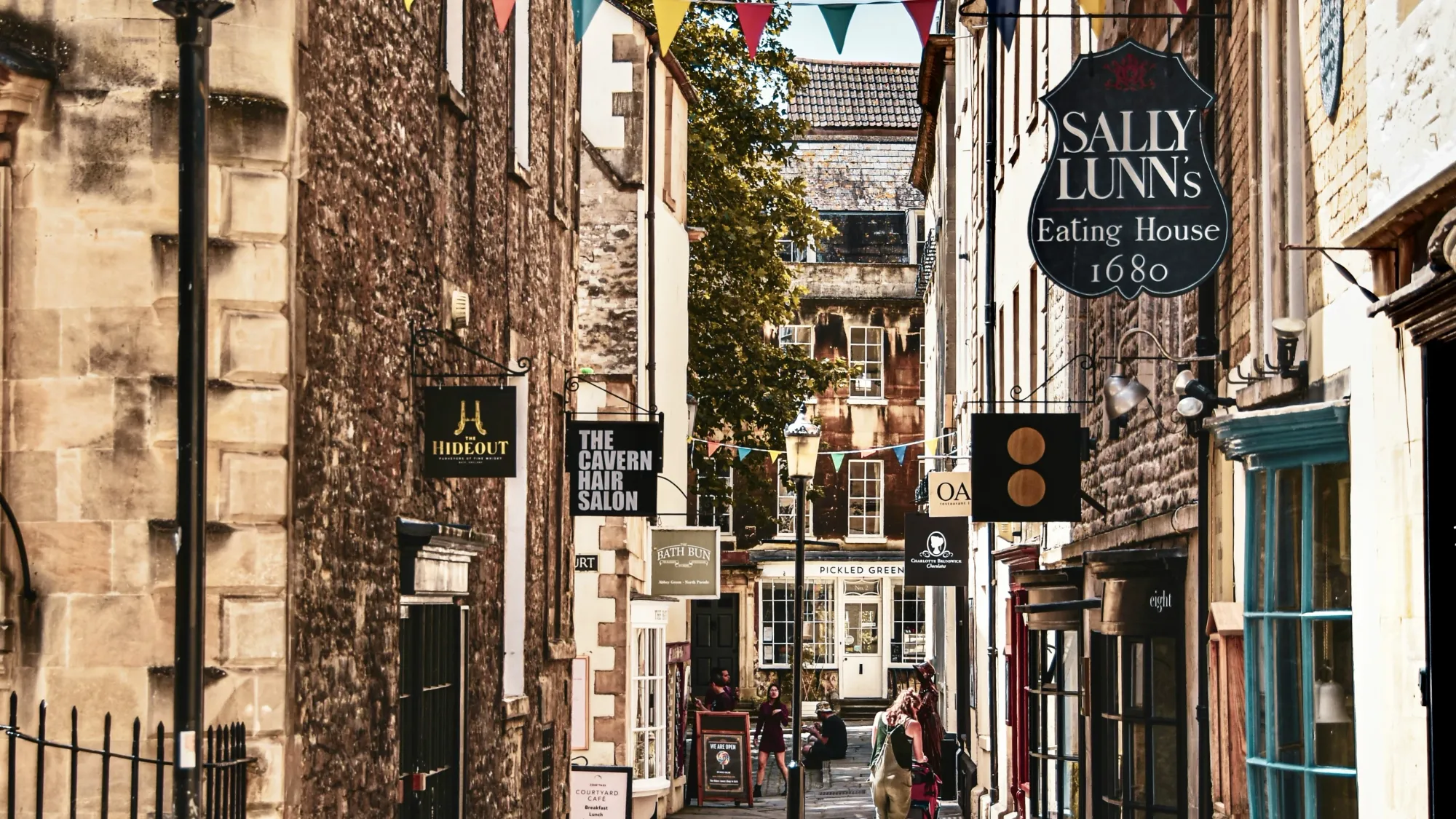 A picturesque street in Bath, England. There is a sign hanging from one of the buildings advertising Sally Lunn's buns, an eatery which has occupied the building in Bath since the year 1680.