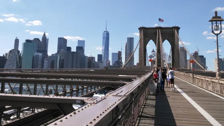 View of the New York City skyline with the Freedom Tower in shot, from the perspective of being in the pedestrian area of the Brooklyn Bridge. 